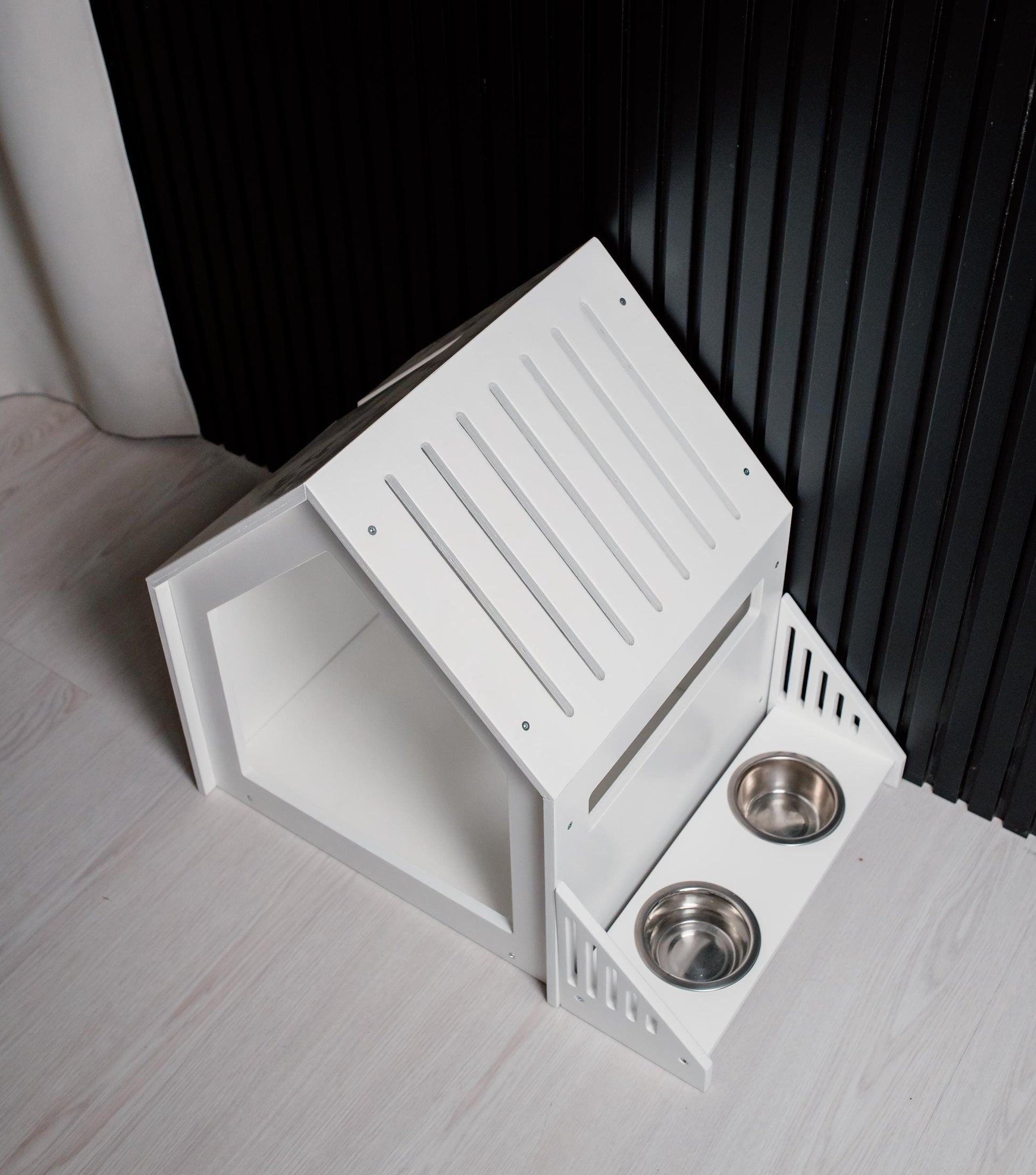 White wooden dog house with raised feeder bowls, compact indoor pet furniture design
